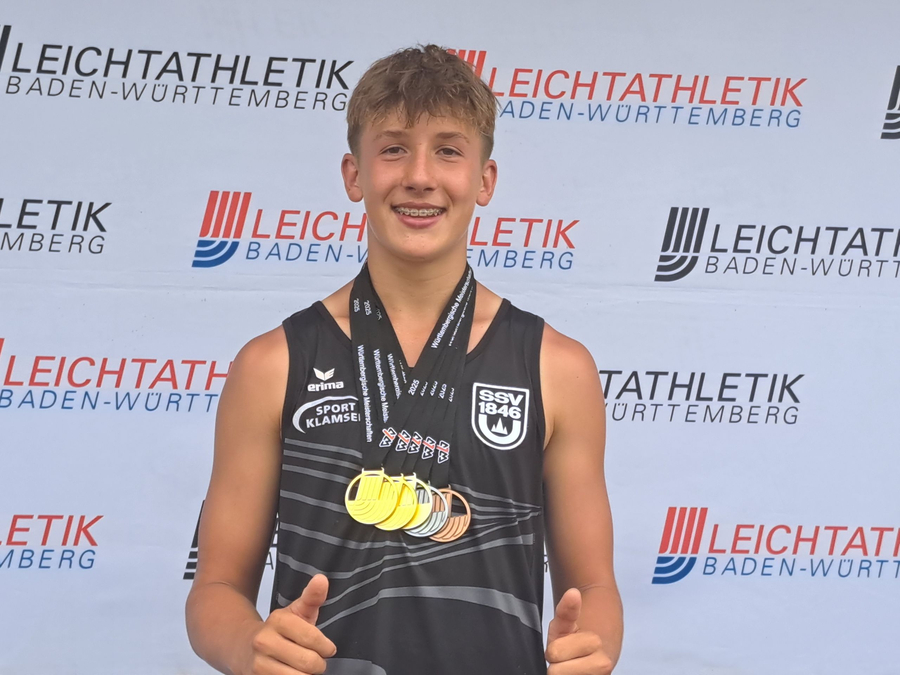 Jugendlicher Athlet mit mehreren Medaillen vor Leichtathletik Baden-Württemberg Banner