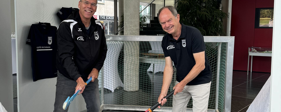 100 Jahre Hockey SSV Ulm 1846 e.V. - Willy Götz und Ortwin Veile - Vorstandschaft Zwei lächelnde Männer mit Hockeyschlägern vor Torrahmen in Ausstellung