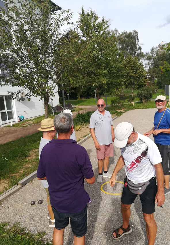 Gruppe älterer Männer spielt Boule auf Kiesbahn