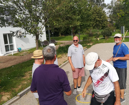 Gruppe älterer Männer spielt Boule auf Kiesbahn
