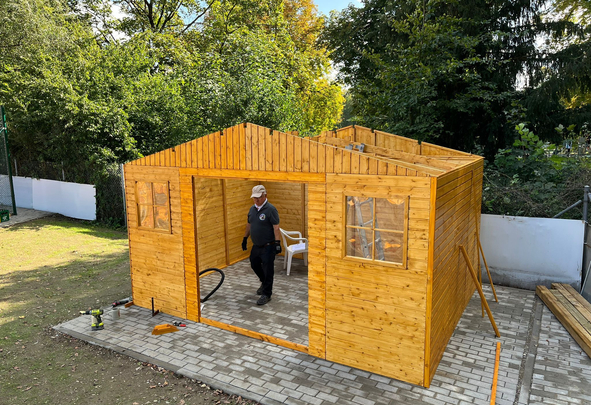Mann baut hölzernes Gartenhaus auf gepflastertem Untergrund