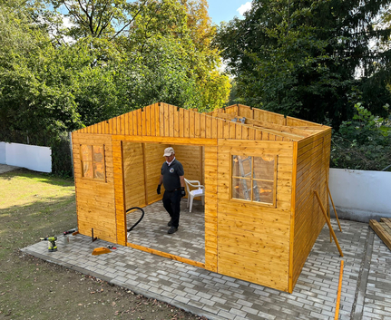 Mann baut hölzernes Gartenhaus auf gepflastertem Untergrund