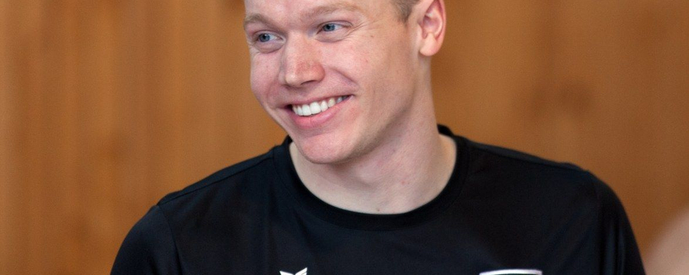 Lächelnder männlicher Schwimmer in schwarzem Vereins-T-Shirt mit Namensschriftzug