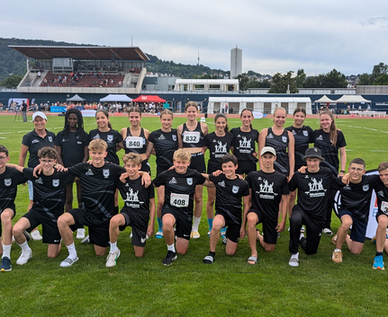 Erfolgreiches Team mit Trainerin Brigitte Hanses U16-Leichtathletikteam posiert auf Stadionrasen nach WLV-Meisterschaften