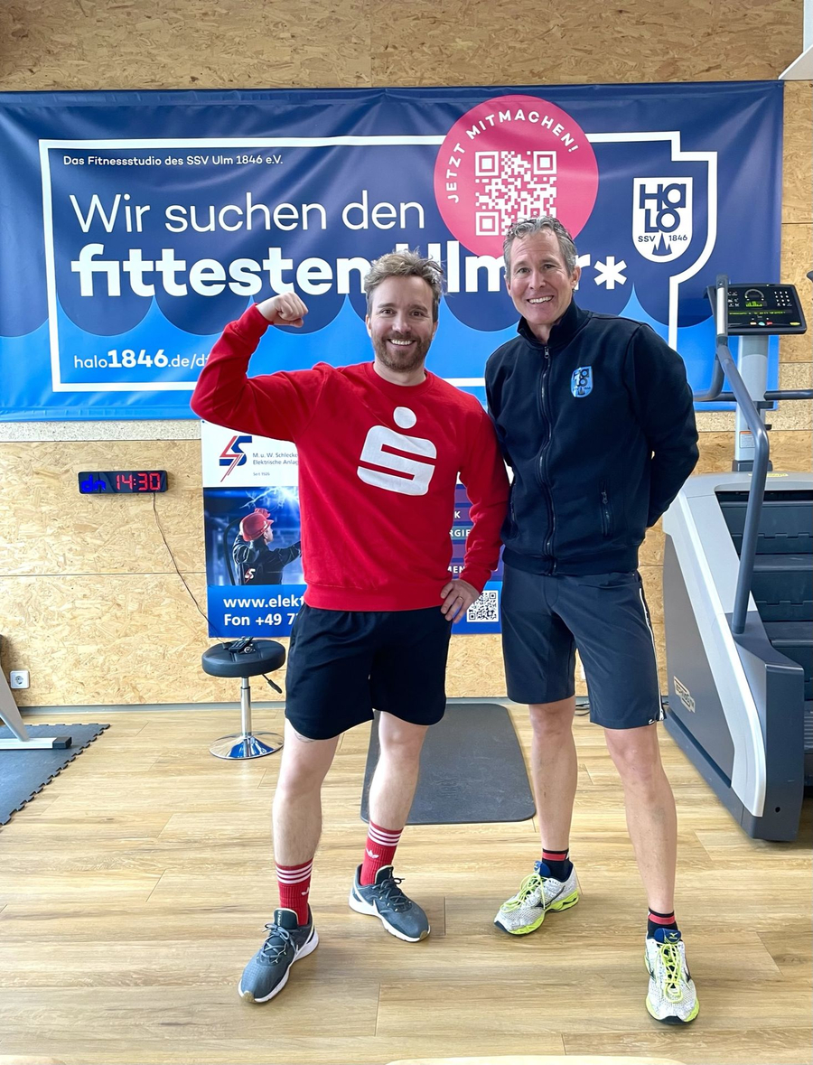 Zwei Männer vor Banner mit Schrift Wir suchen den fittesten Ulmer*