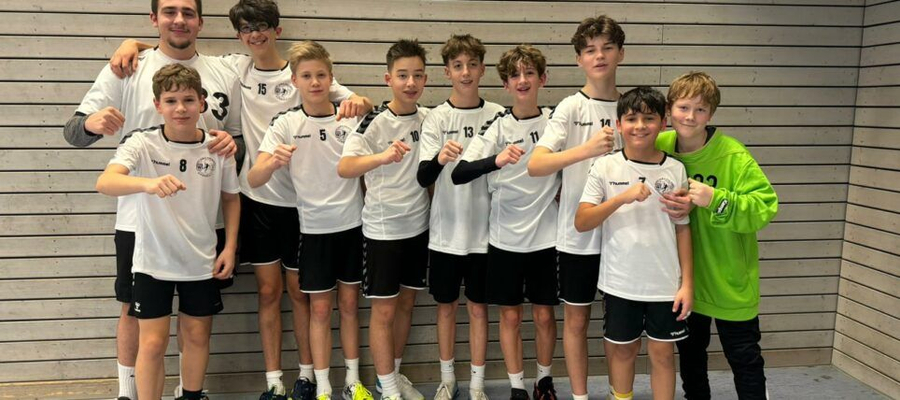 Männliche C-Jugend Handballmannschaft posiert mit Trainer in Halle