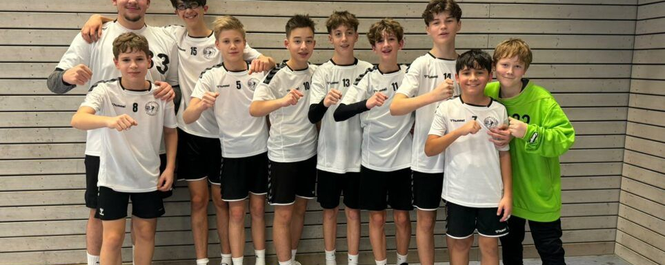 Männliche C-Jugend Handballmannschaft posiert mit Trainer in Halle