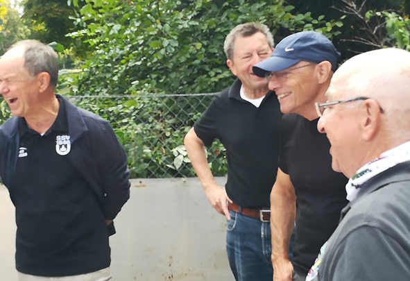 Four older men laughing together outdoors