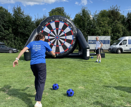 Person tritt Ball auf große aufblasbare Dartscheibe