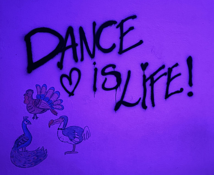 Violett beleuchtete Wand mit DANCE ♥ is LIFE Graffiti und Tierzeichnungen