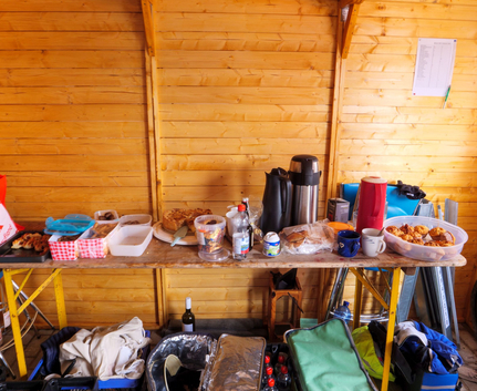 Tisch in Holzhütte mit Kuchen, Brot, Thermoskannen und Muffins