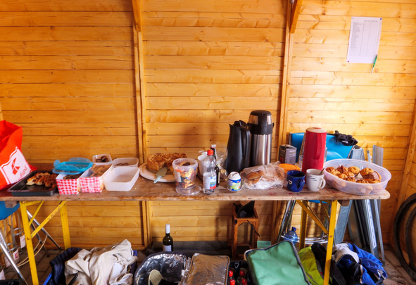 Tisch in Holzhütte mit Kuchen, Brot, Thermoskannen und Muffins
