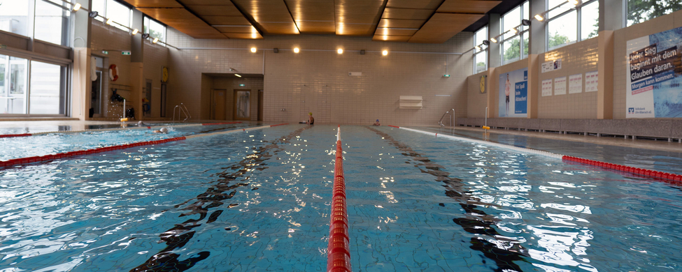Hallenbadbecken mit rotem Bahnteiler und leeren Schwimmbahnen