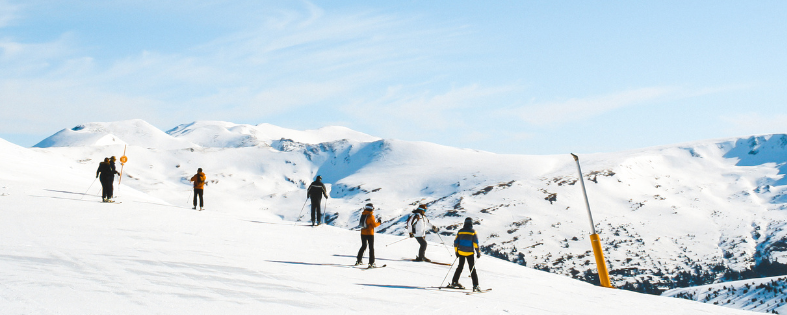 Mehrere Skifahrer auf schneebedecktem Berghang bei klarem Himmel