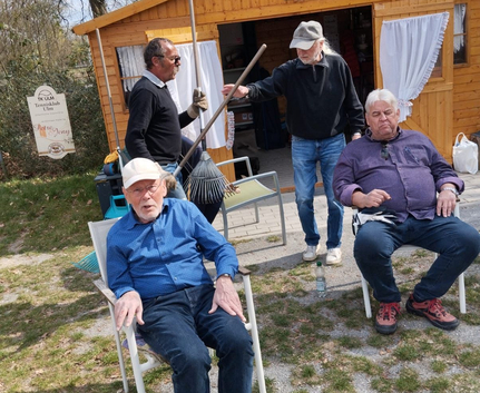 Vier Männer vor Holzhütte mit Harken bei Reinigungsaktion