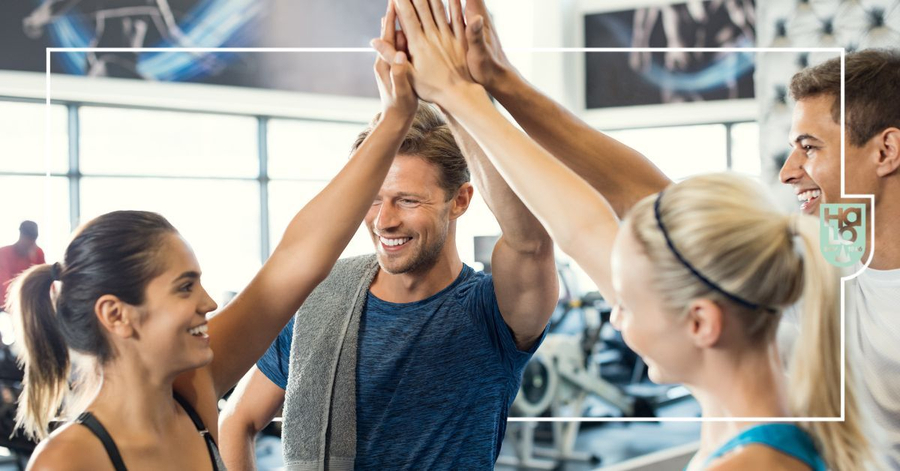 Vier Sportler im Fitnessstudio beim gemeinsamen Highfive