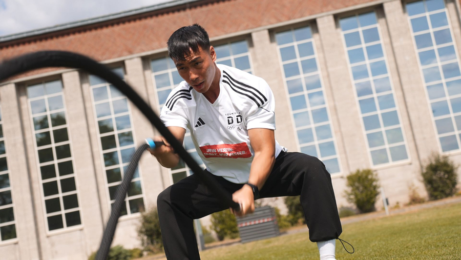 Person beim Battle-ropes Training im Freien vor Sporthalle