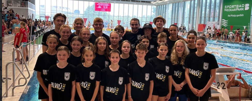 Jugendliches Schwimmteam posiert am Beckenrand in Hallenbad
