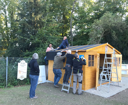 Mehrere Personen montieren Dach auf Holzschuppen
