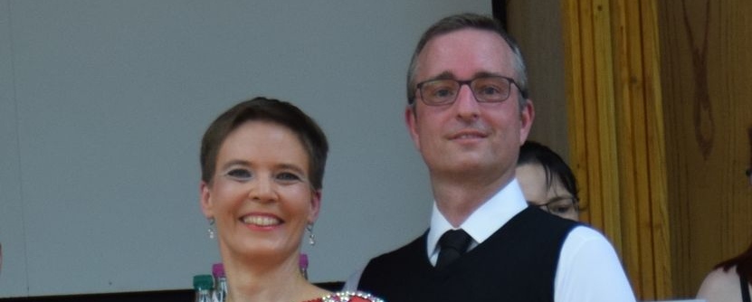 Tanzpaar auf Platz eins Frau in rotem Kleid hält Urkunde