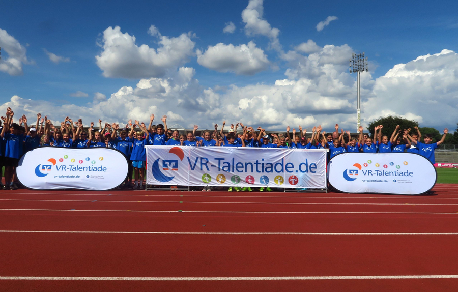 Kinder in blauen Trikots hinter Banner mit Aufschrift VR-Talentiade