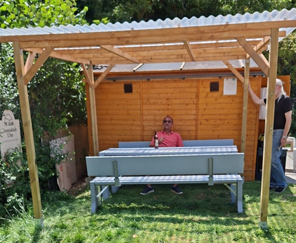 Überdachter Sitzbereich an der Vereinshütte mit Person
