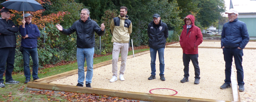 Männer auf Bouleplatz im Regen bei Eröffnungsfest einer gestikuliert