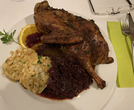 Geröstetes Geflügel mit Knödeln Rotkohl und Orangenscheibe