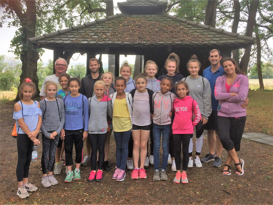 Juniorinnen und Trainer vor hölzerner Hütte Schriftzug BE YOU sichtbar