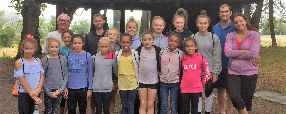 Juniorinnen und Trainer vor hölzerner Hütte Schriftzug BE YOU sichtbar