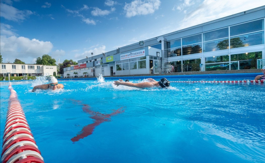 Zwei Schwimmer trainieren in benachbarten Bahnen eines Freibads