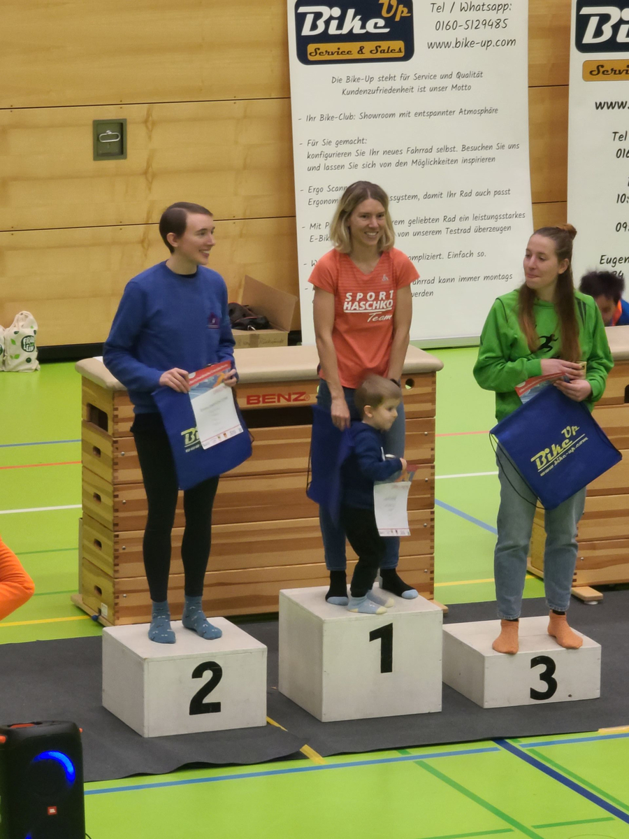 Drei Läuferinnen bei Siegerehrung mit Kleinkind auf Platz eins