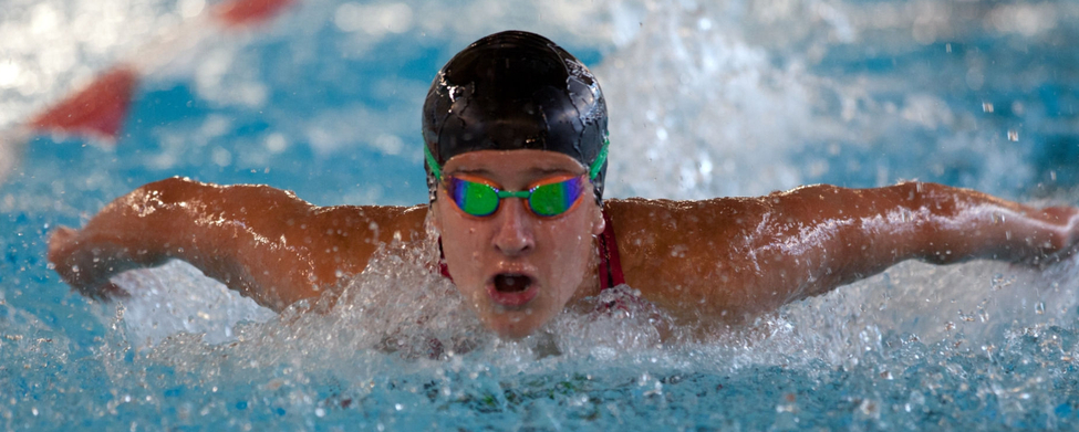 Schwimmer mit Schwimmkappe und Schwimmbrille beim Schmetterlingsschwimmen im Wettkampf