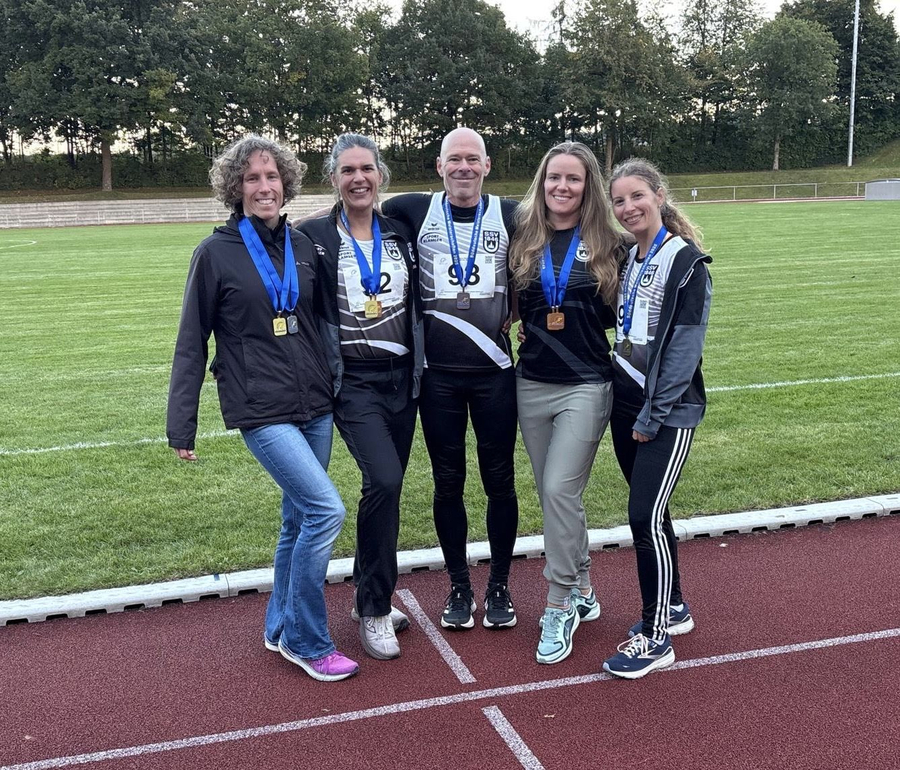 Gruppe aus vier Athletinnen und einem Athleten mit Medaillen auf Laufbahn