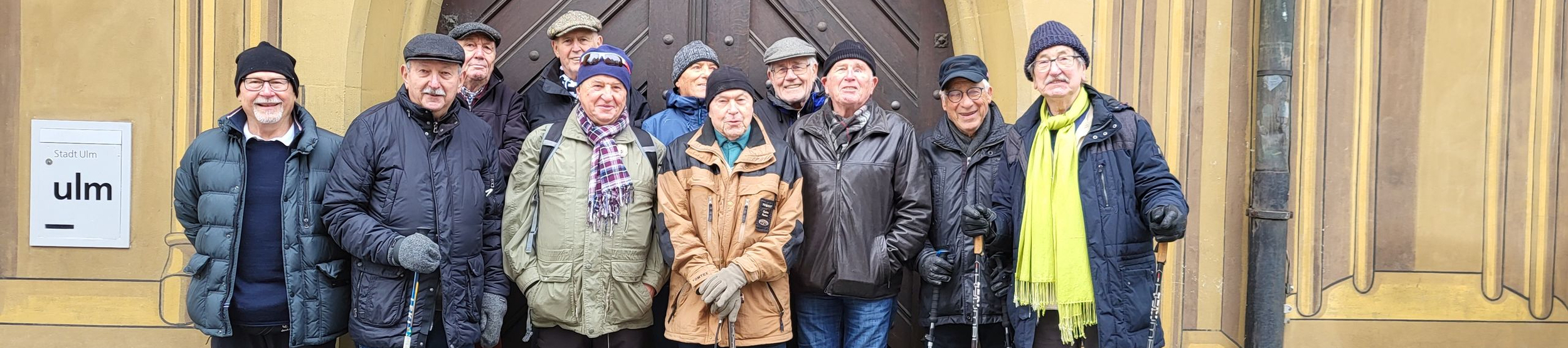 Ältere Wandergruppe mit Wanderstöcken vor historischem Portal