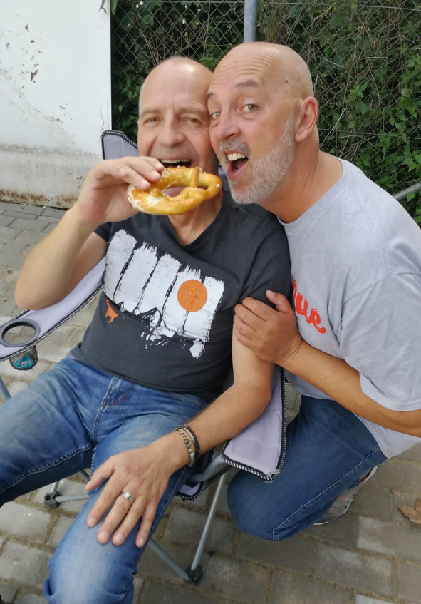 Zwei Männer einer isst eine Brezel der andere beugt sich heran