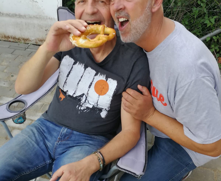 Zwei Männer einer isst eine Brezel der andere beugt sich heran