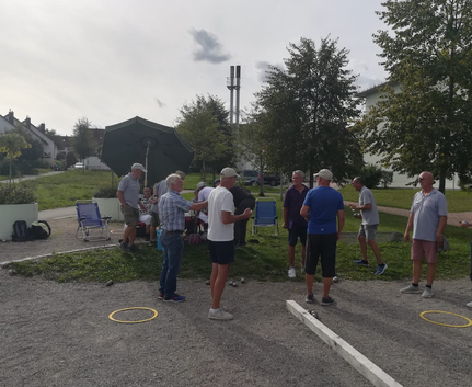 Mehrere Männer und Frauen spielen Boule auf Kiesplatz im Park