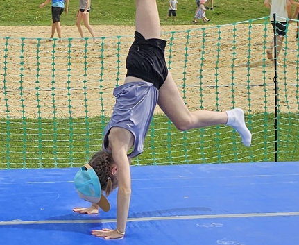 Kind macht Handstand auf blauer Matte beim Mitmach-Sportfest