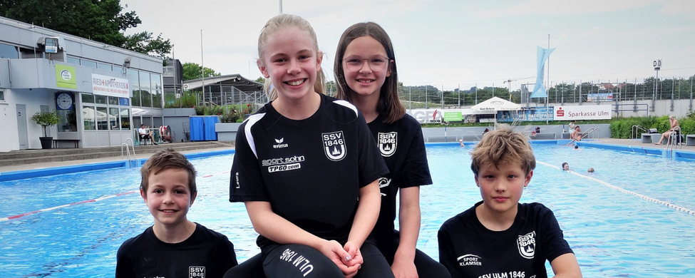 Vier junge Schwimmer in SSV Ulm 1846 Shirts am Freibadrand beim Landesvielseitigkeitstest