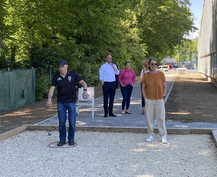 Man throwing a metal boule while four others watch