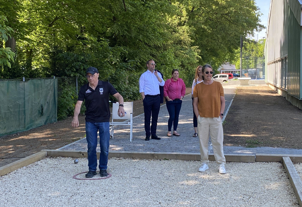 Man throwing a metal boule while four others watch