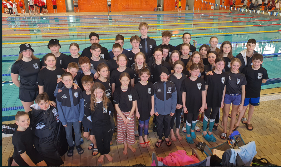Ulmer Schwimmteam in Vereinskleidung lächelnd am Beckenrand