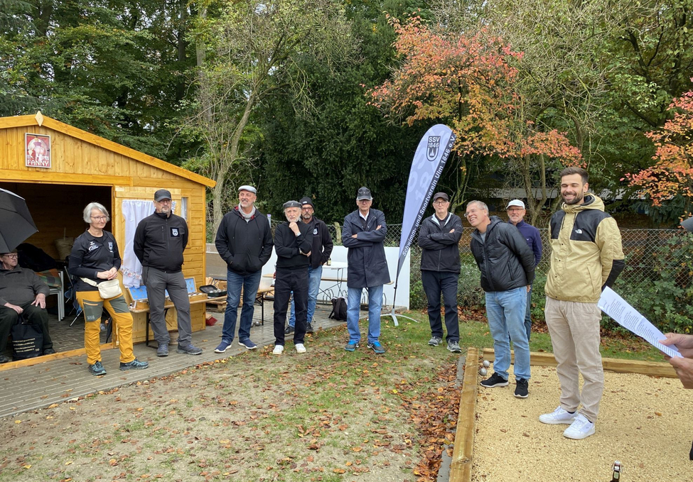 Erwachsene Gruppe steht vor Holzhütte und Fahne im Herbst