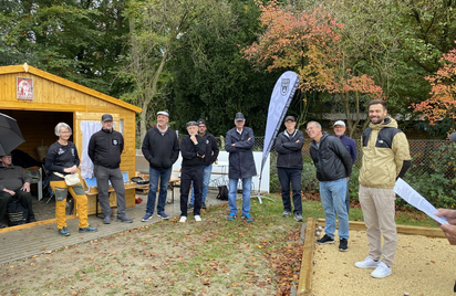 Erwachsene Gruppe steht vor Holzhütte und Fahne im Herbst