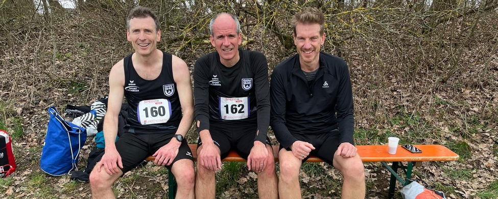 Three runners sitting on bench with bibs 160 and 162