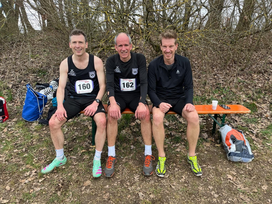 Three runners sitting on bench with bibs 160 and 162