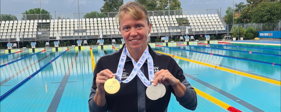 Schwimmerin am Beckenrand hält Gold- und Silbermedaille