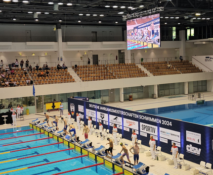 Startende Schwimmer vor Banner Deutsche Jahrgangsmeisterschaften Schwimmen 2024
