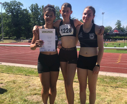 Luna Drayton, Johanna Baierl, Laura Schmidt Drei junge Athletinnen auf Sportplatz mit URKUNDE und Startnummer 1228